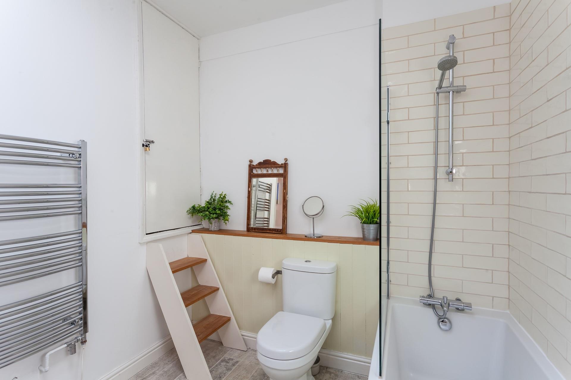 The cute and quaint bathroom benefits from both a bath and a shower over.