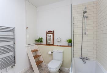 The cute and quaint bathroom benefits from both a bath and a shower over.