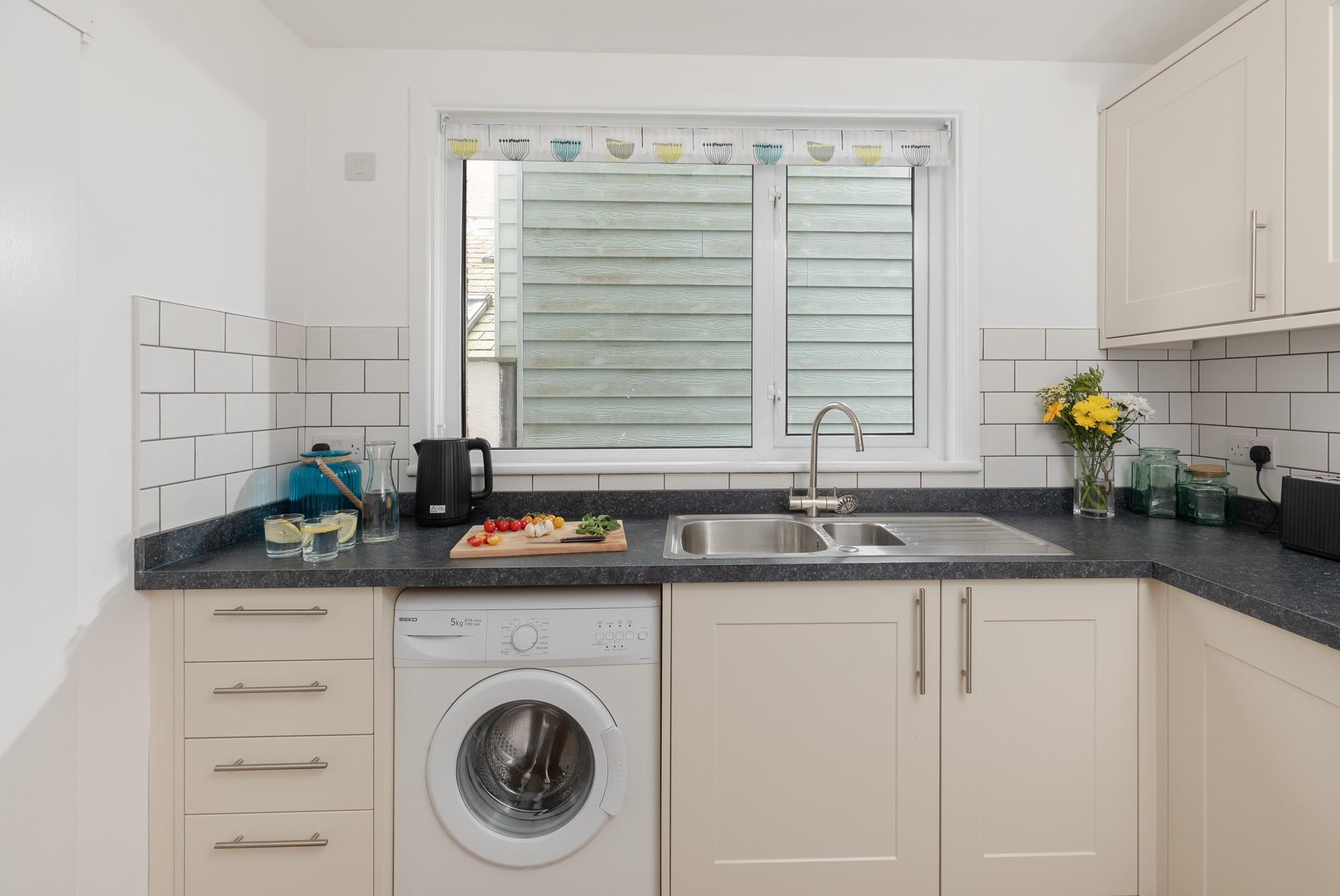 The kitchen is well-equipped with a microwave, electric oven and hob, washing machine and fridge/freezer. 