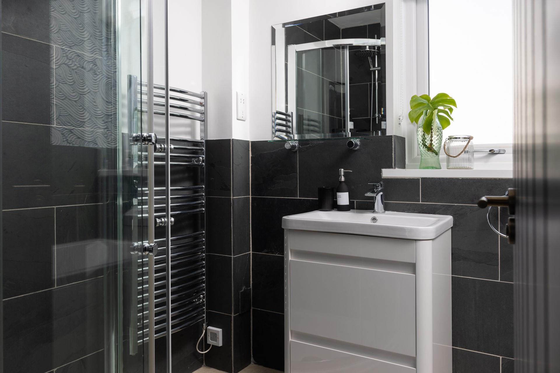 A monochromatic colour palette and modern fixtures give the bathroom a stylish feel.