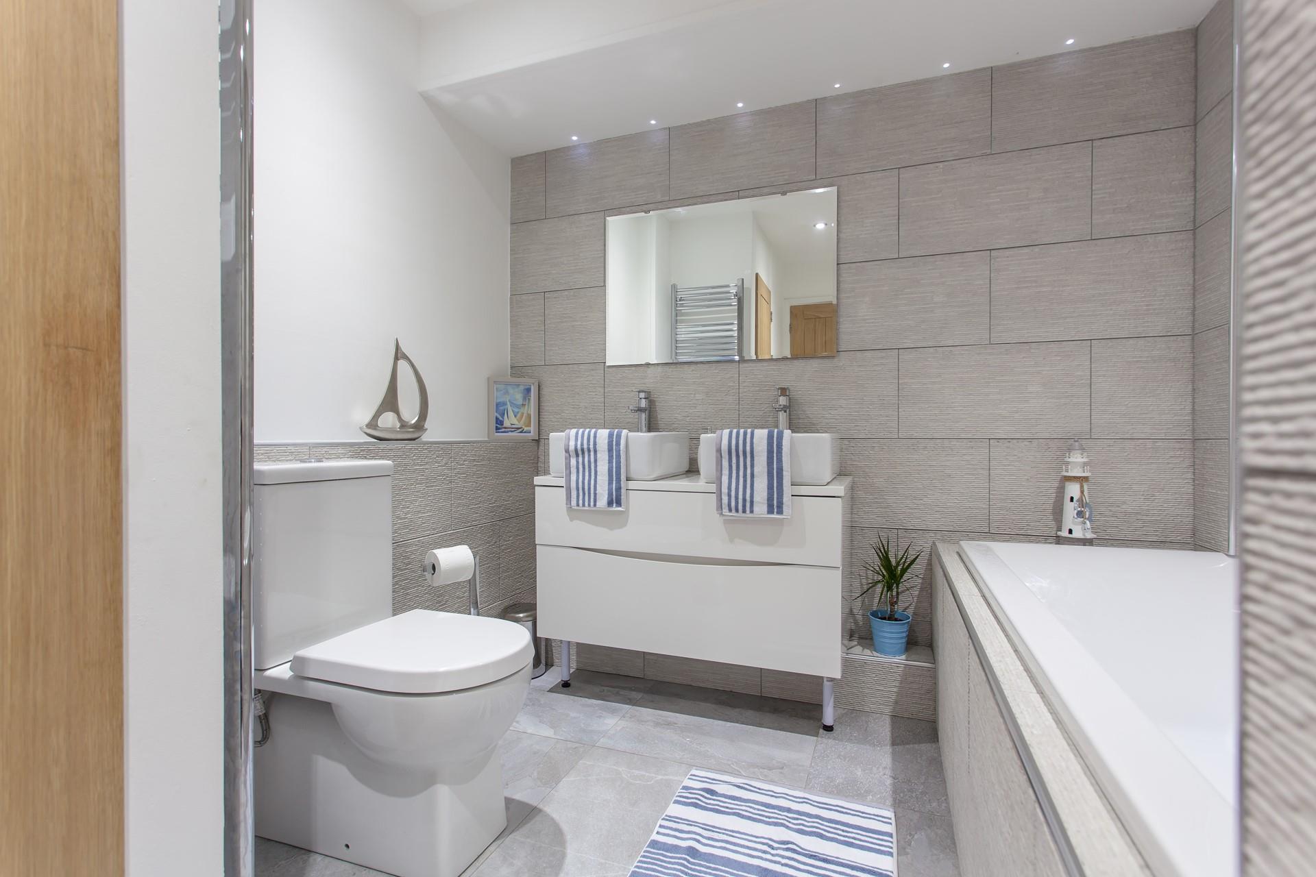 The family bathroom has a beautiful, sleek and stylish finish. 