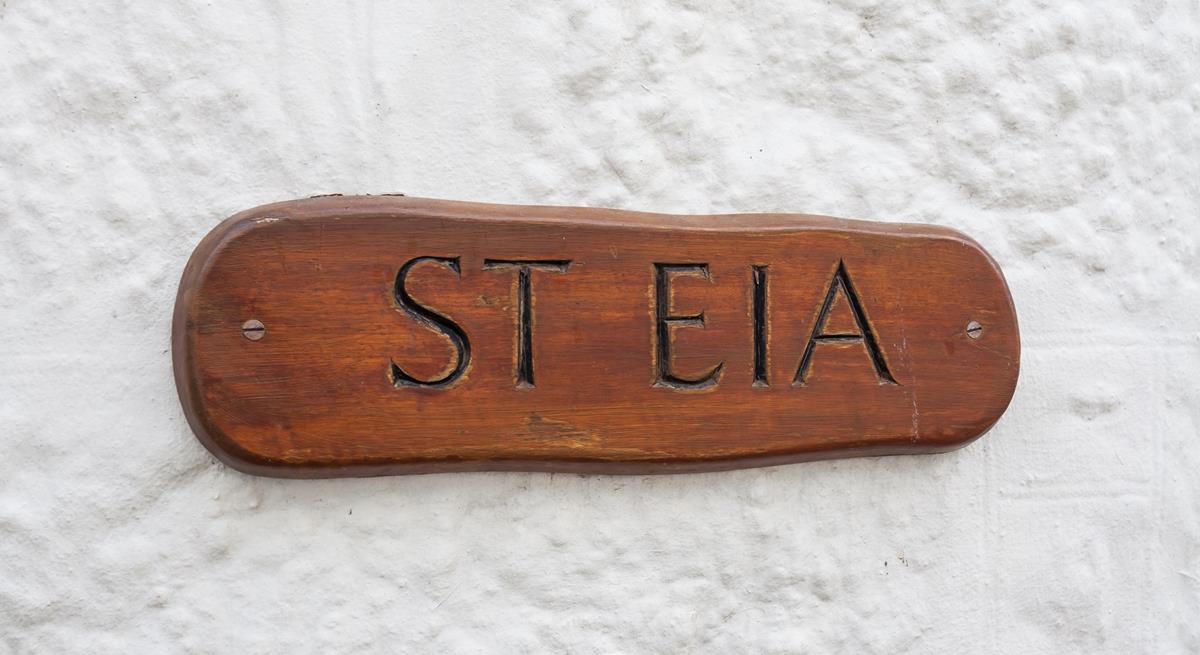 The cottage has a traditional whitewashed exterior and the wooden property sign looks great.