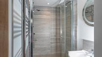 The shower room has a spacious walk-in shower and basin, and is located on the ground floor.