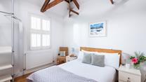 Bedroom 1 has a calming decor and exposed natural wood beams.