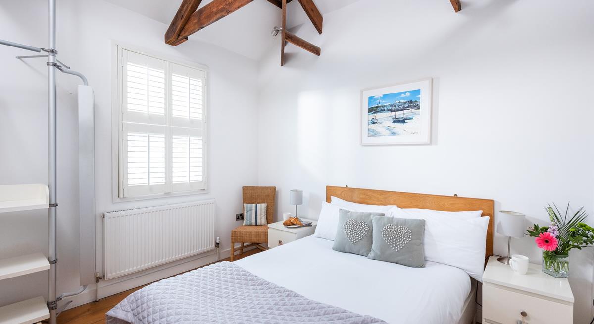 Bedroom 1 has a calming decor and exposed natural wood beams.