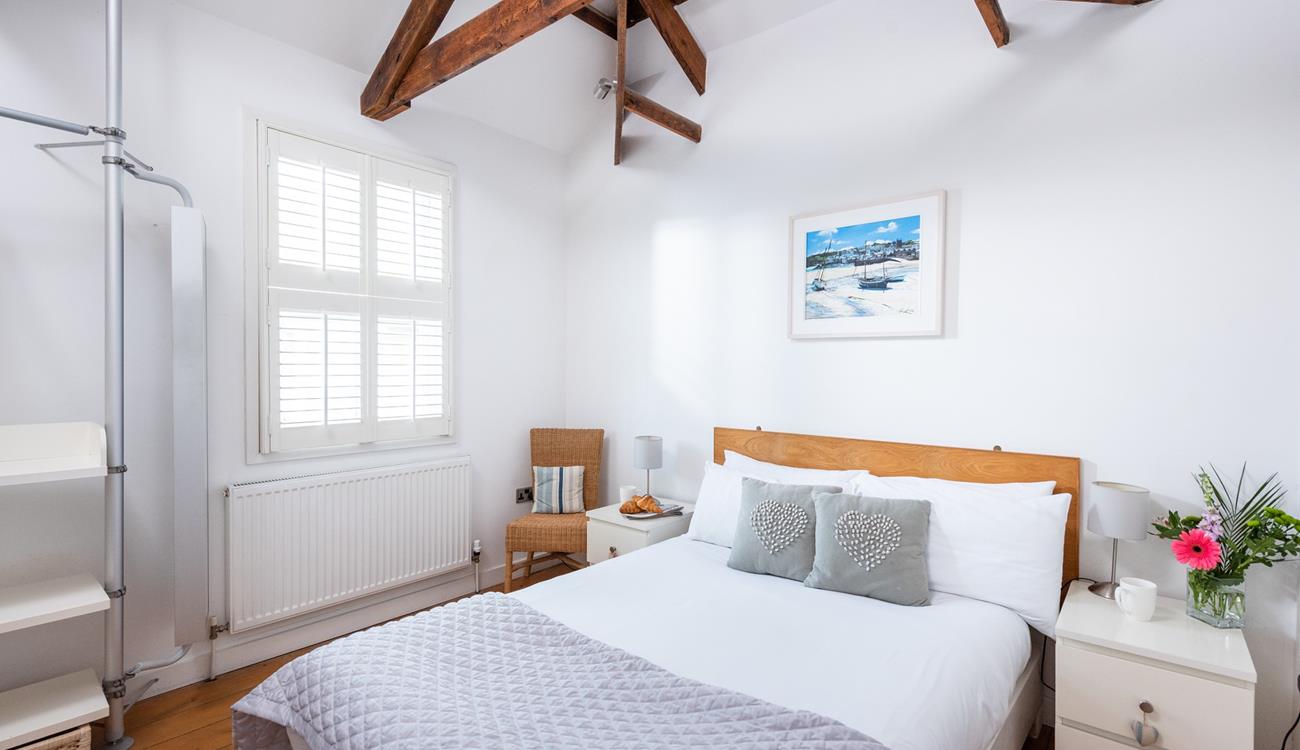 Bedroom 1 has a calming decor and exposed natural wood beams.