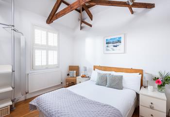Bedroom 1 has a calming decor and exposed natural wood beams.