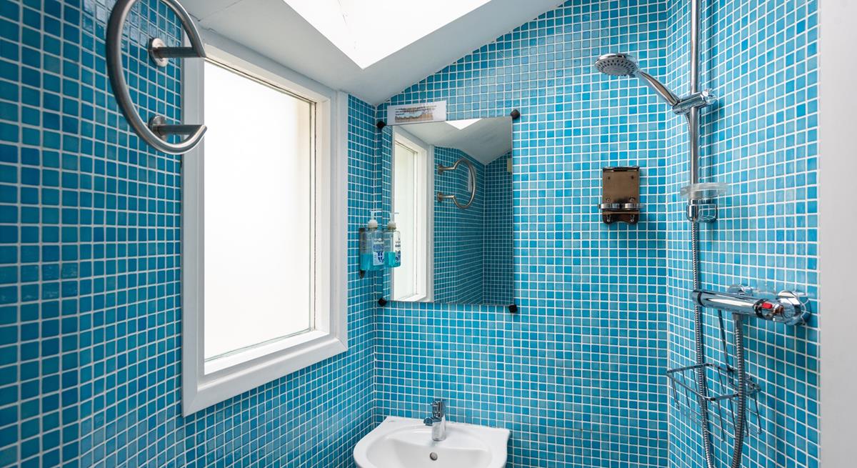 The ground floor wet room is fully tiled in a cool blue mosaic tiling, perfect for washing off sandy toes.