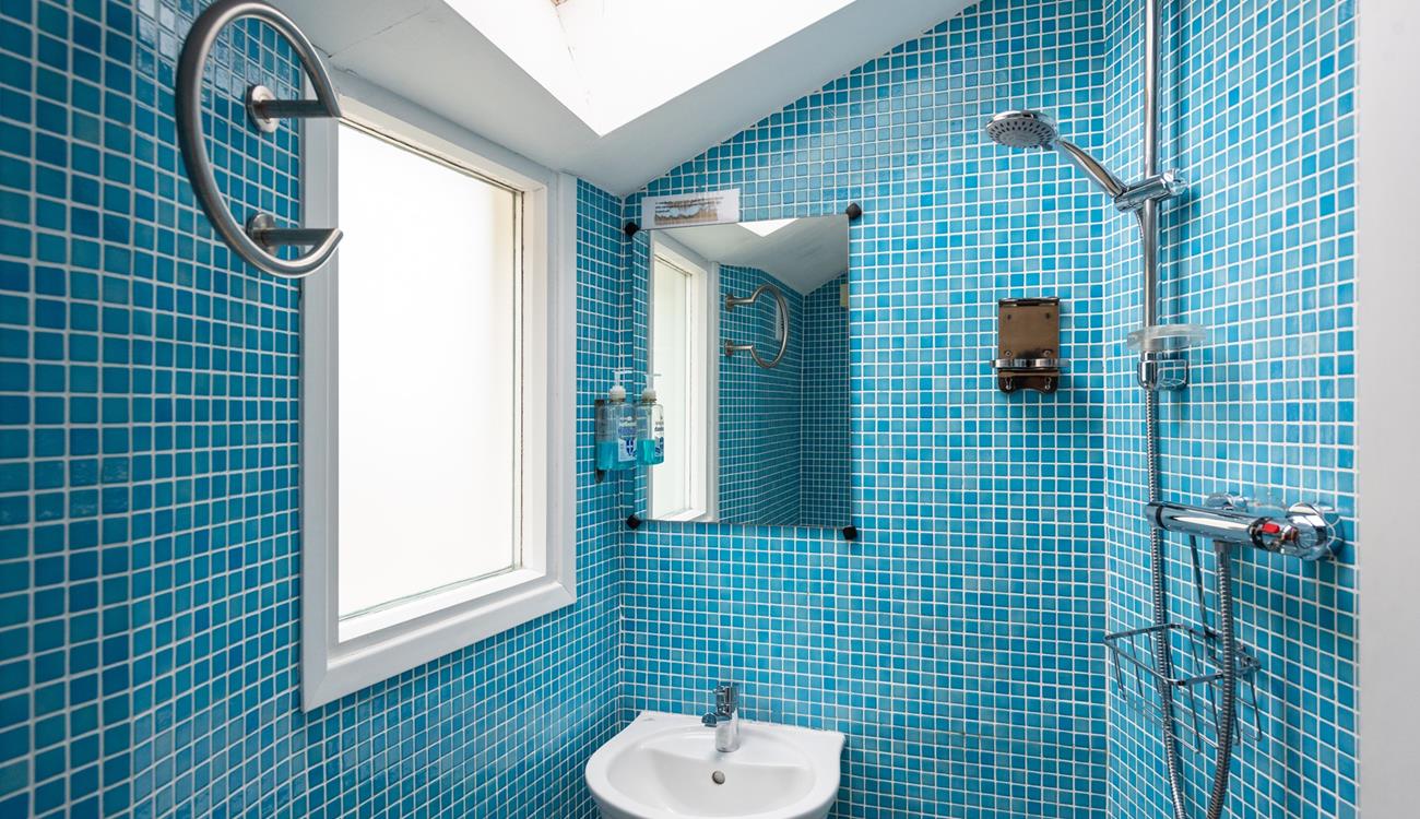 The ground floor wet room is fully tiled in a cool blue mosaic tiling, perfect for washing off sandy toes.