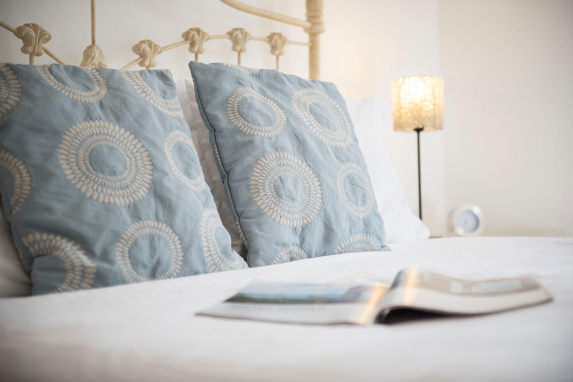Enjoy restful nights of sleep in this cosy bed, crisp white linen and blue patterned accent cushions. 