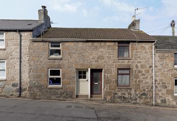The cottage features rustic Cornish stone and a cream door and windows. 