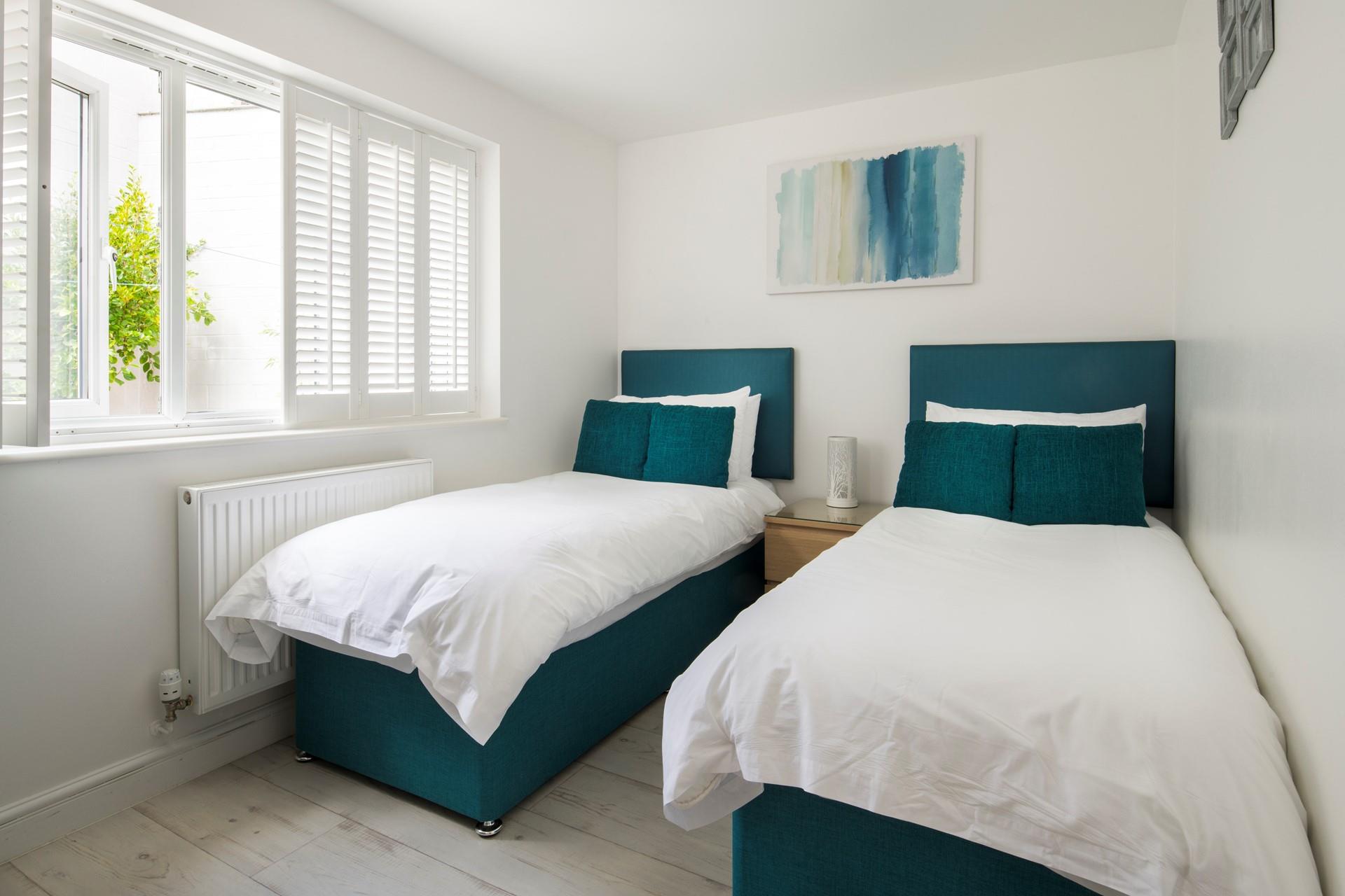 The classic white shutters give an elegant finish to this stylish twin room. 