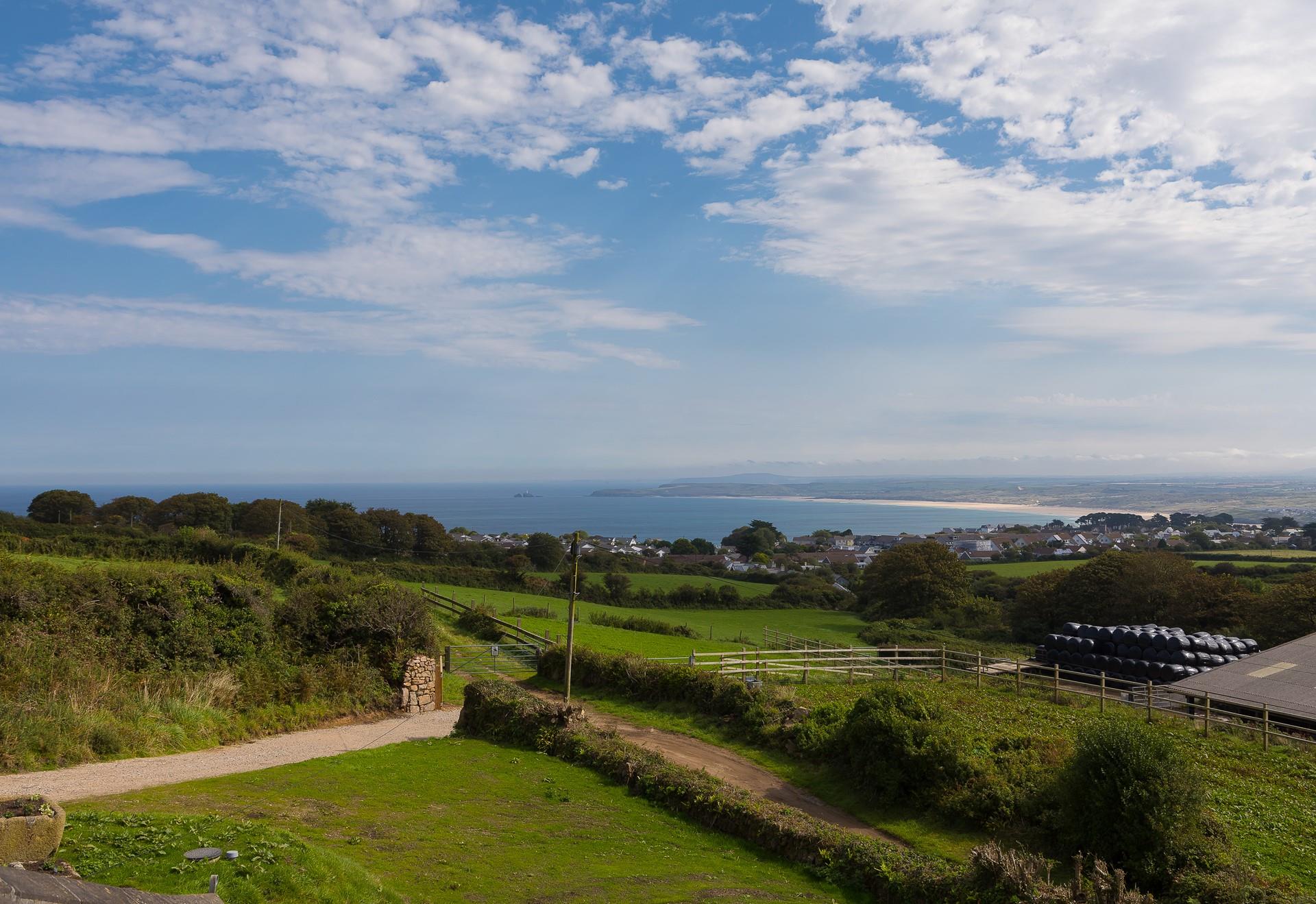 The view unfurls through the farming countryside, towards the coastline.