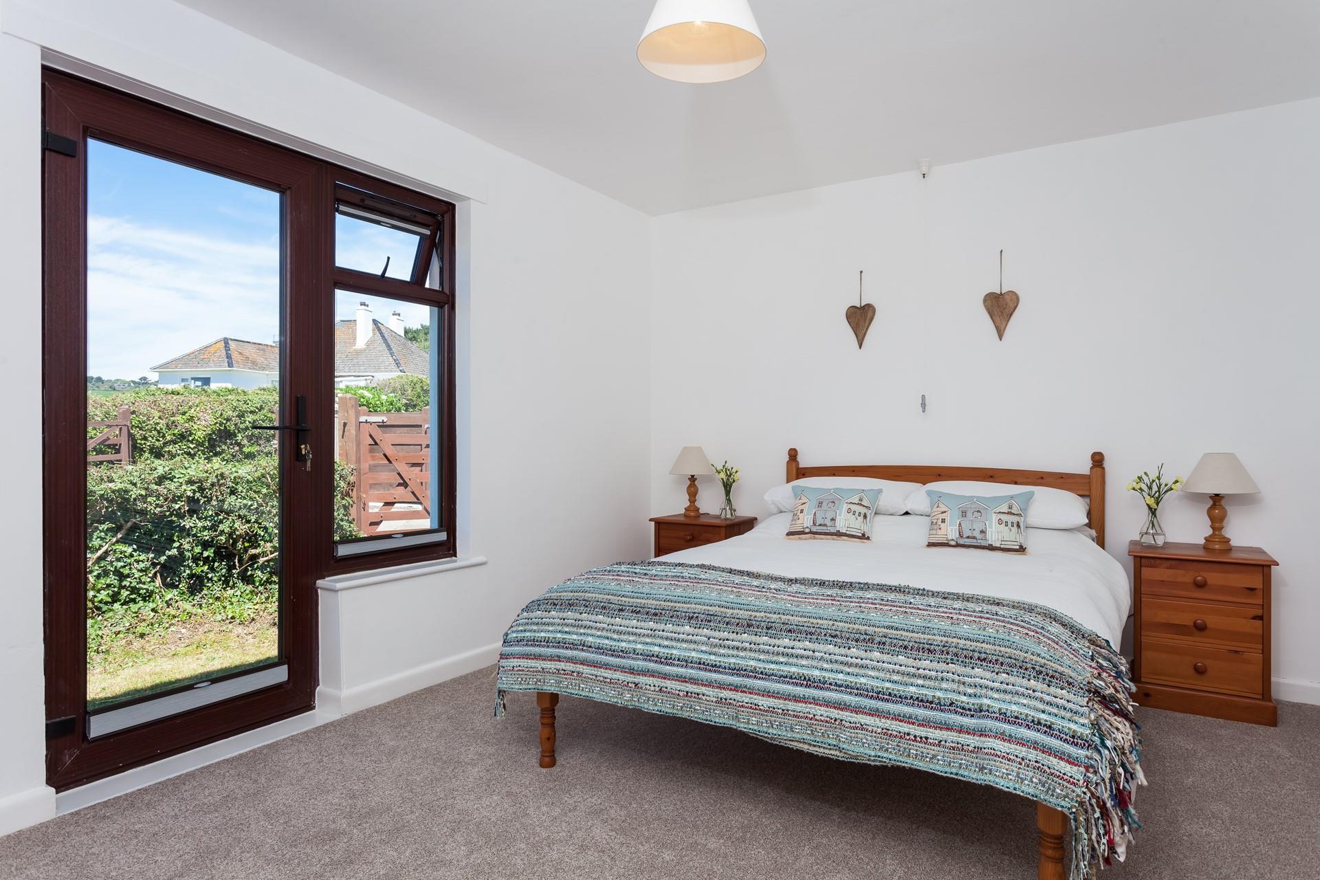The master bedroom is complete with a comfortable double bed and a door leading out to the side garden.