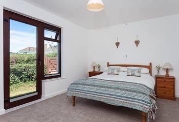 The master bedroom is complete with a comfortable double bed and a door leading out to the side garden.