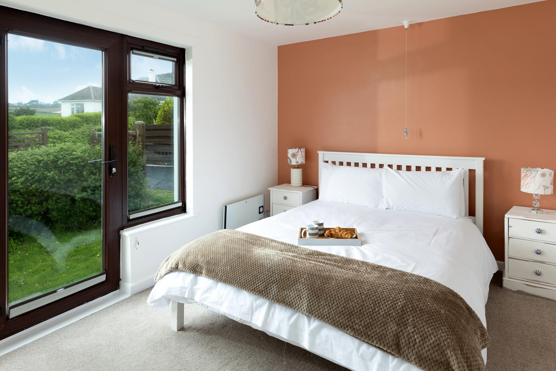 The master bedroom is complete with a comfortable bed and a door leading out to the side garden.