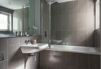 The family bathroom is sleek and modern with a bath and rainfall shower over and cosy underfloor heating.