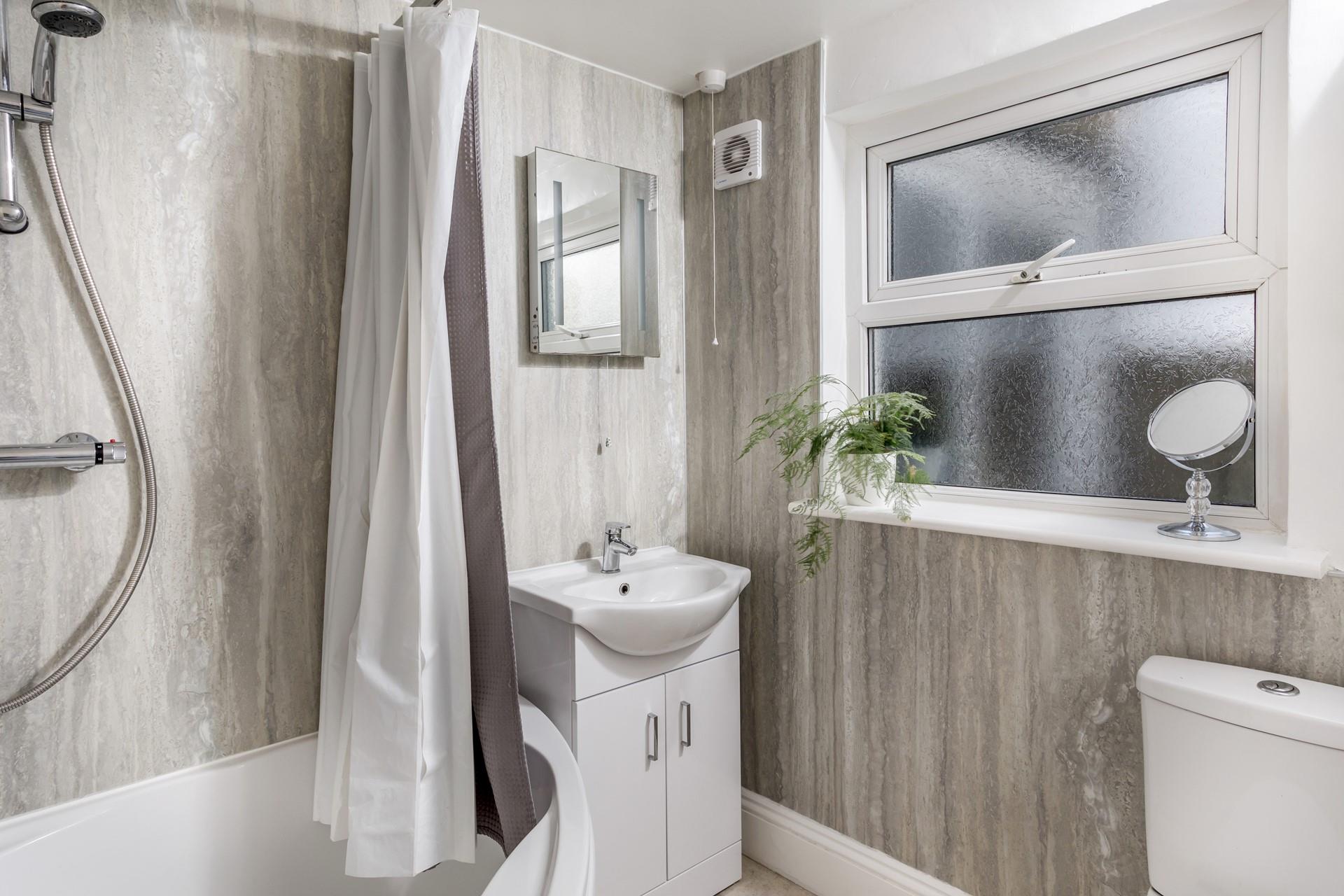 The family bathroom has a corner bath with seat, ideal for a relaxing soak after a long day at the beach.