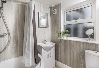 The family bathroom has a corner bath with seat, ideal for a relaxing soak after a long day at the beach.
