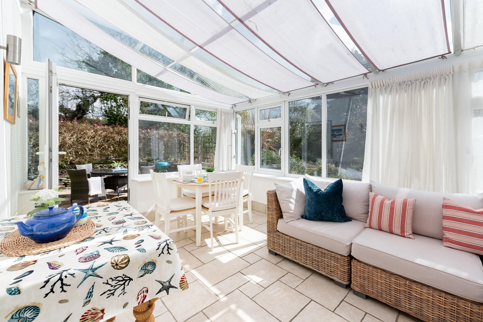 Large conservatory with comfortable seating, perfect for relaxing with a bottle of wine.