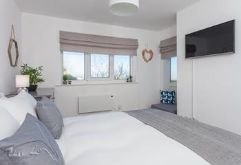 Elegant and stylish, this beautifully finished bedroom features large windows and a large Smart TV. 