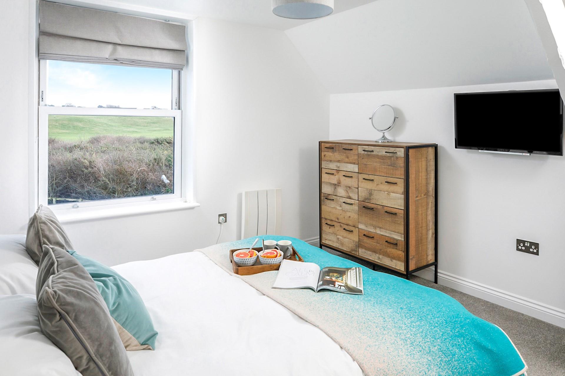 Stylishly designed bedroom 1 has calming colours and views over the golf course to wake up to each day.
