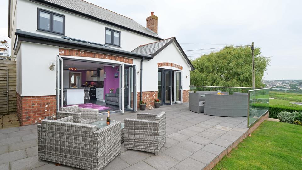 The rear of The Grange features bi-fold doors and patio doors leading out to the large patio and lawn area. 
