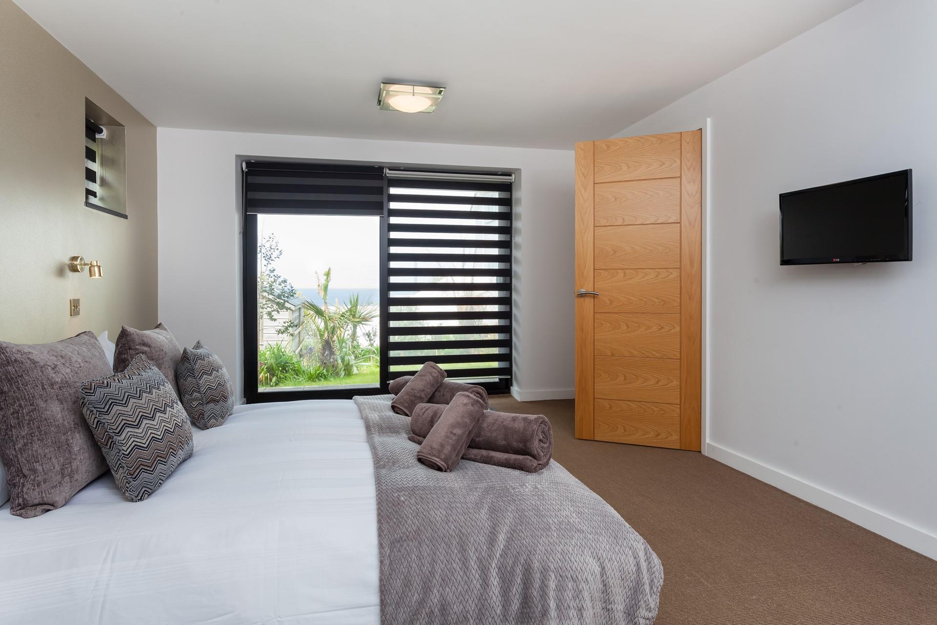 Bedroom 3 has a king size bed with a wall-mounted TV and a sea view across St Ives bay.