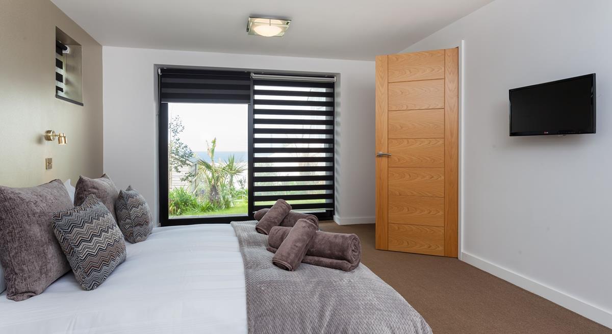 Bedroom 3 has a king size bed with a wall-mounted TV and a sea view across St Ives bay.