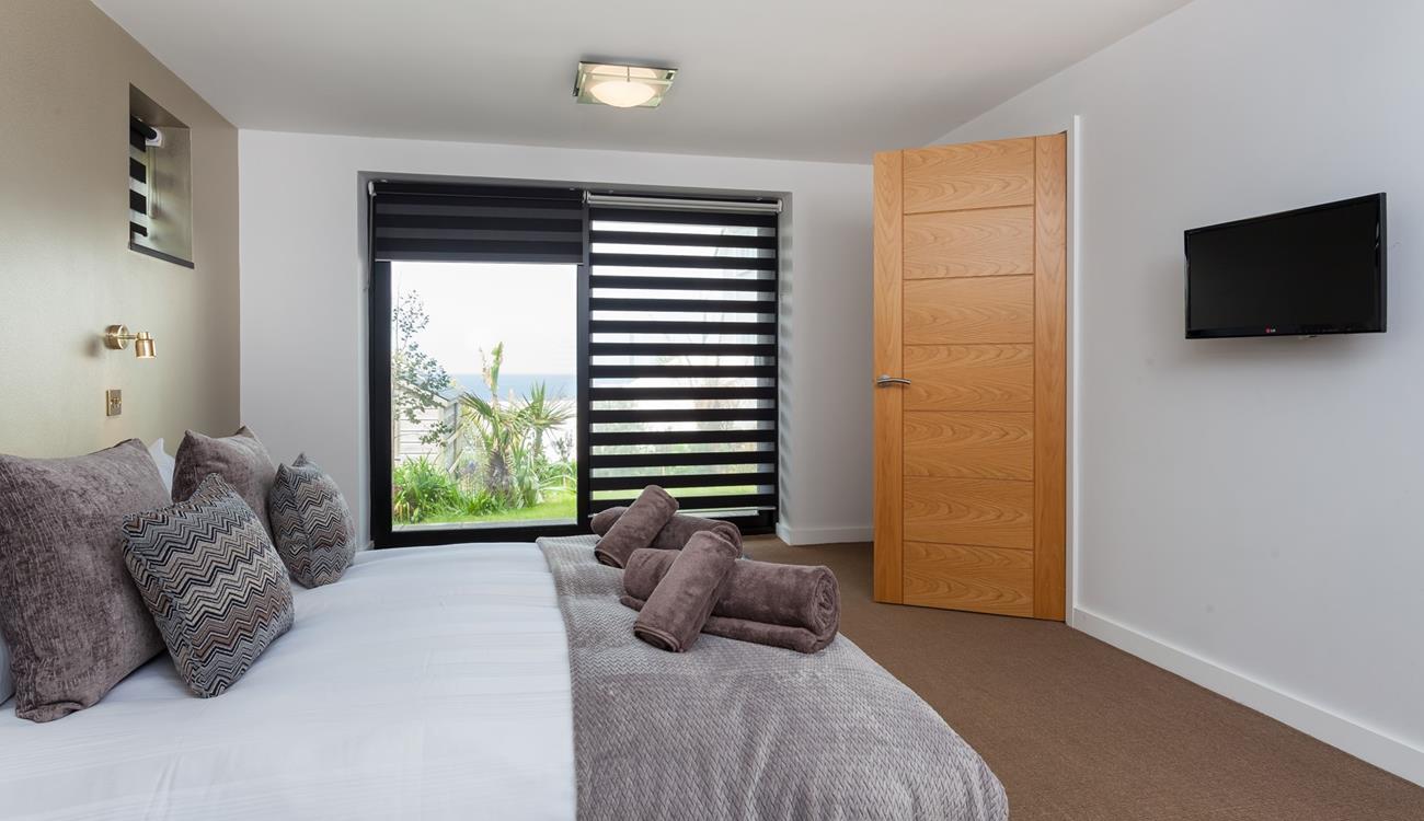 Bedroom 3 has a king size bed with a wall-mounted TV and a sea view across St Ives bay.