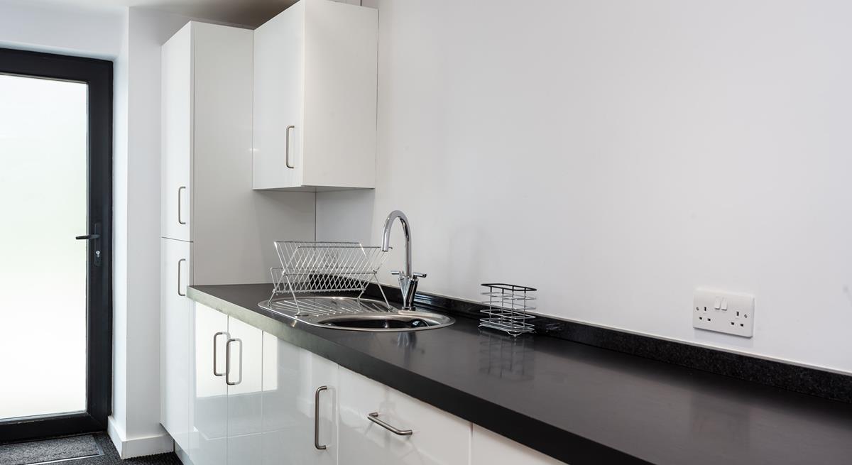 The utility area is sleek and has an ample worktop, a sink with a drainer and several cupboards for extra storage.