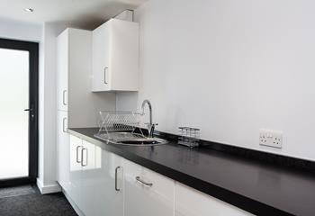 The utility area is sleek and has an ample worktop, a sink with a drainer and several cupboards for extra storage.