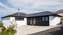 The approach and driveway at Higher Carthew is very open plan, with a dark stained timber-clad entrance wall.