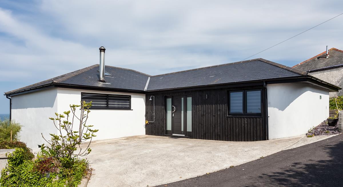 The approach and driveway at Higher Carthew is very open plan, with a dark stained timber-clad entrance wall.