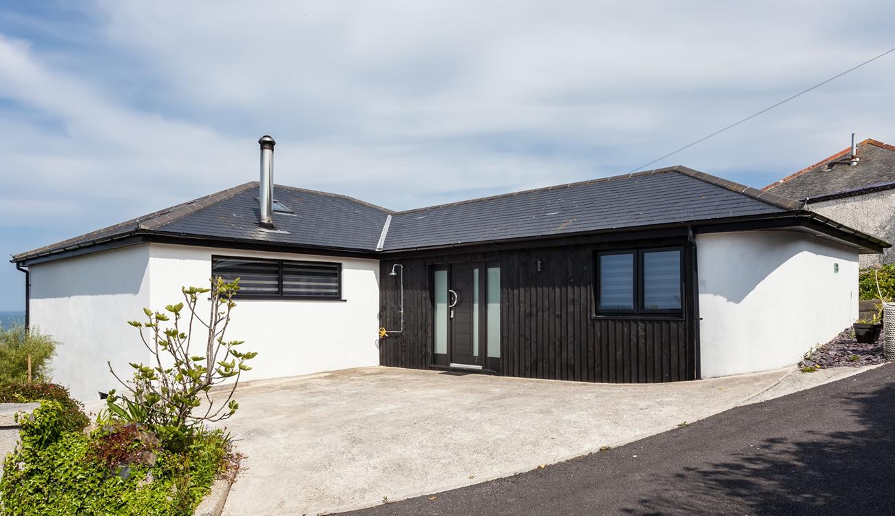 The approach and driveway at Higher Carthew is very open plan, with a dark stained timber-clad entrance wall.