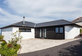 The approach and driveway at Higher Carthew is very open plan, with a dark stained timber-clad entrance wall.
