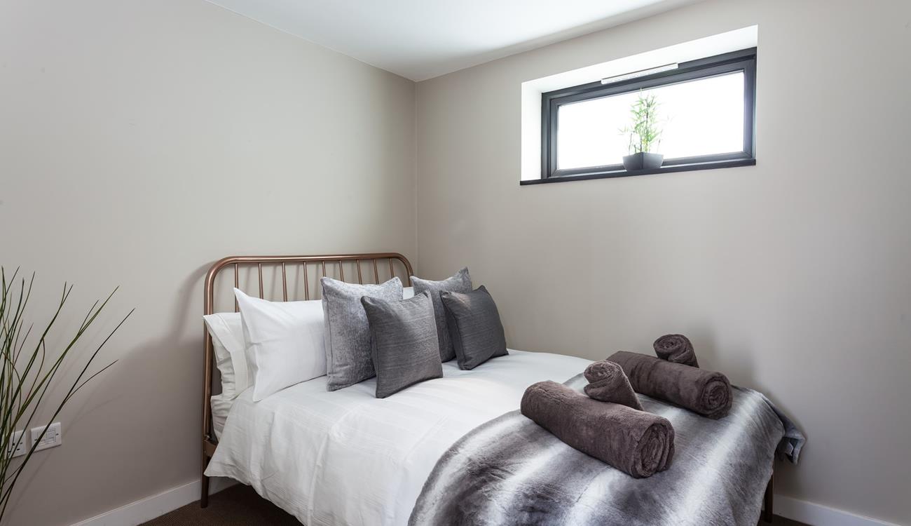 Bedroom 2 has a contemporary grey decor for a calming space to relax.