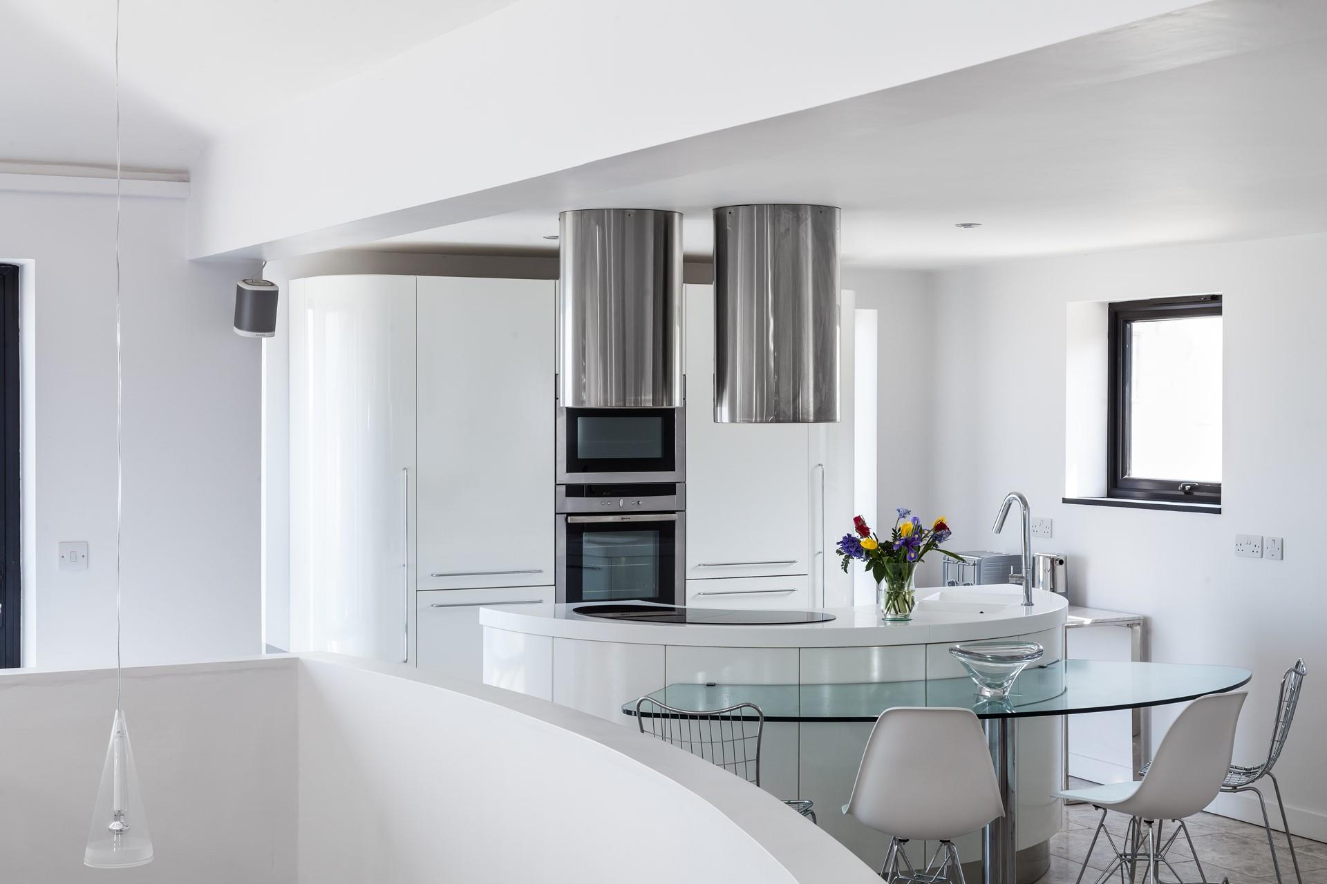 Curved contemporary lines have created a fantastic kitchen area in the living space, which captures pure light and angles.
