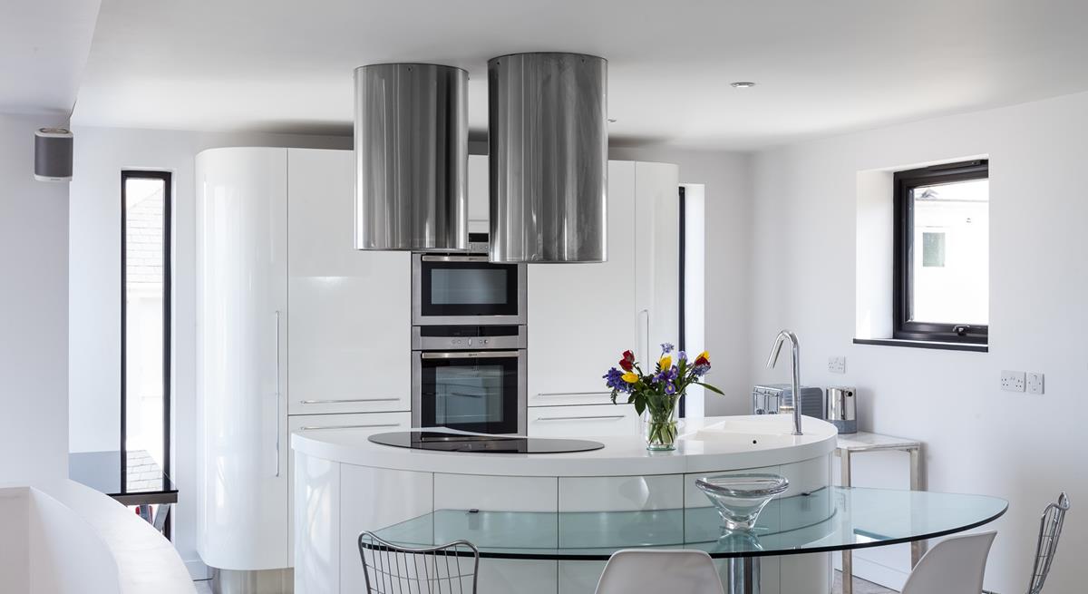 Full-length vertical windows run each side of the main kitchen cupboards, offering lots of natural light.