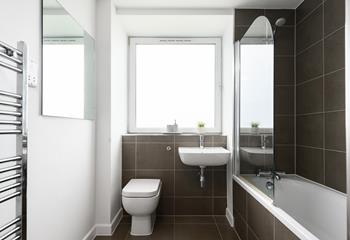 The bathroom's modern tiles create a calming, indulgent atmosphere.