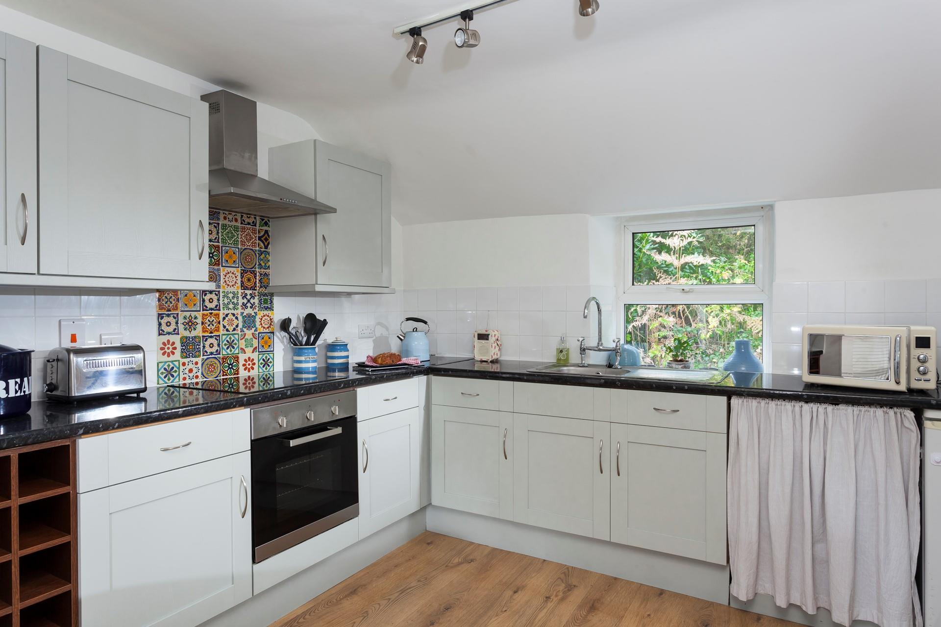The kitchen is modern and fully equipped with bright mosaic tiles.