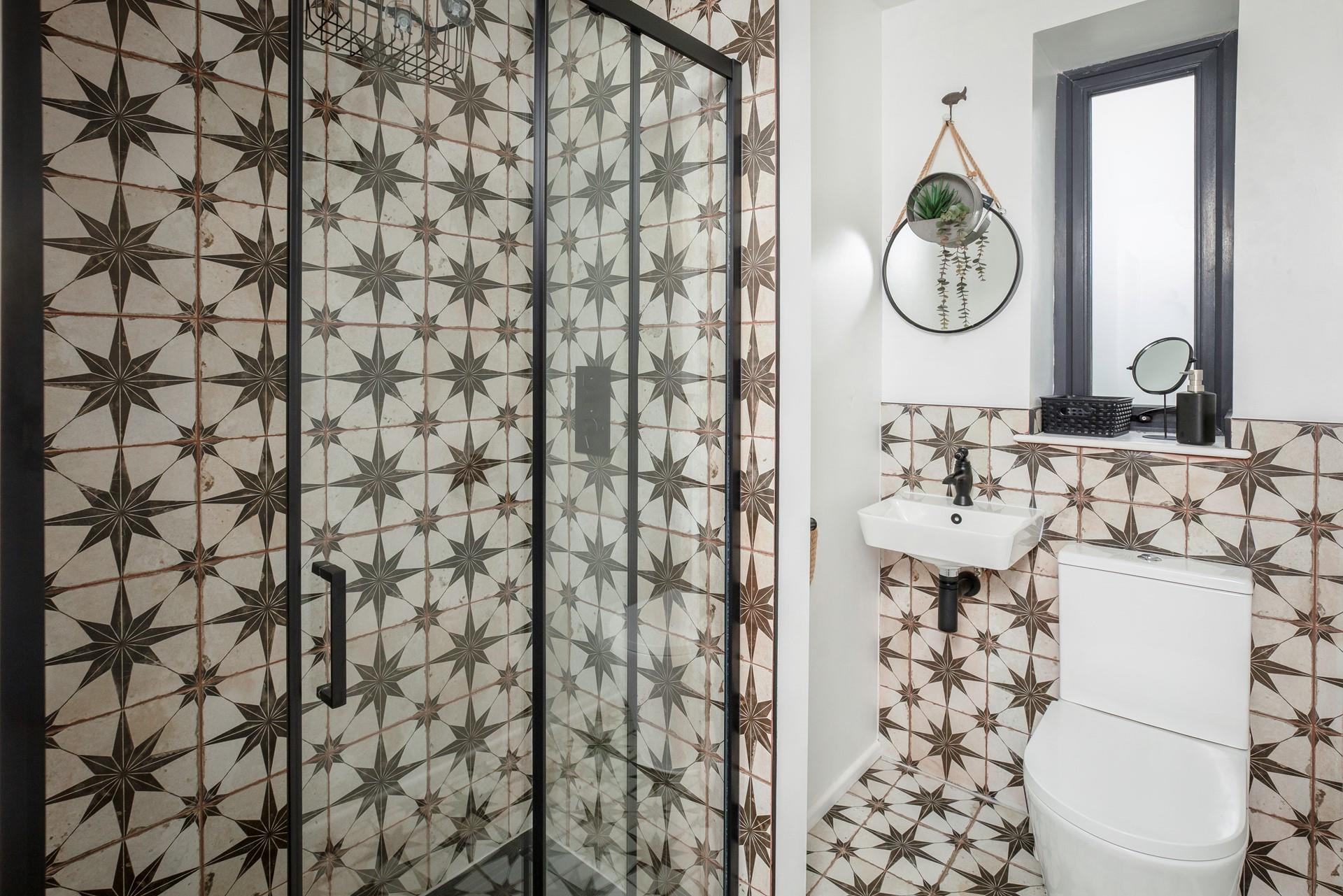 The shower room has mosaic tiles and is stylishly decorated.