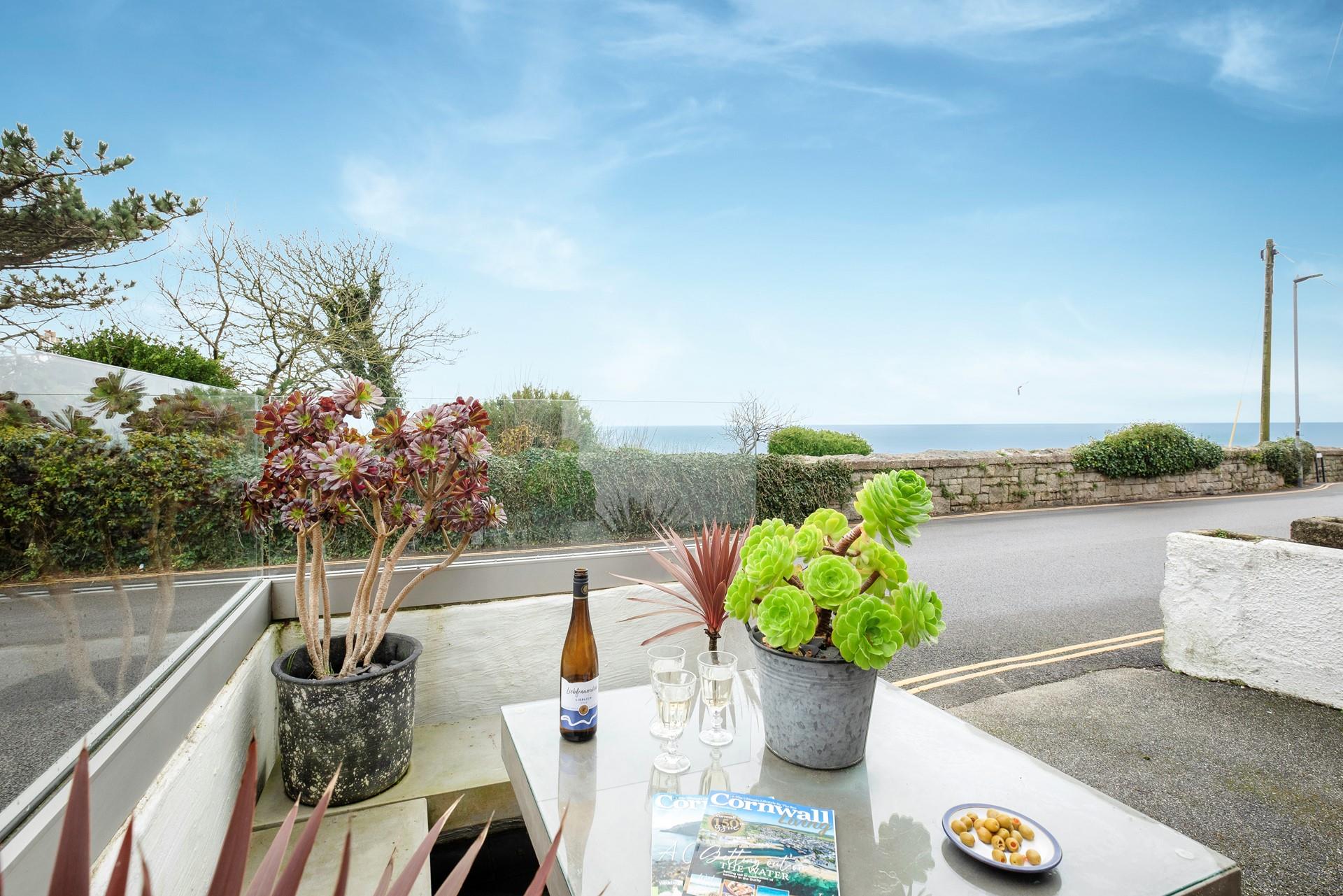 At the front of the property, there is a bijou stone seating area with two benches and a stone dining table with a glass top.