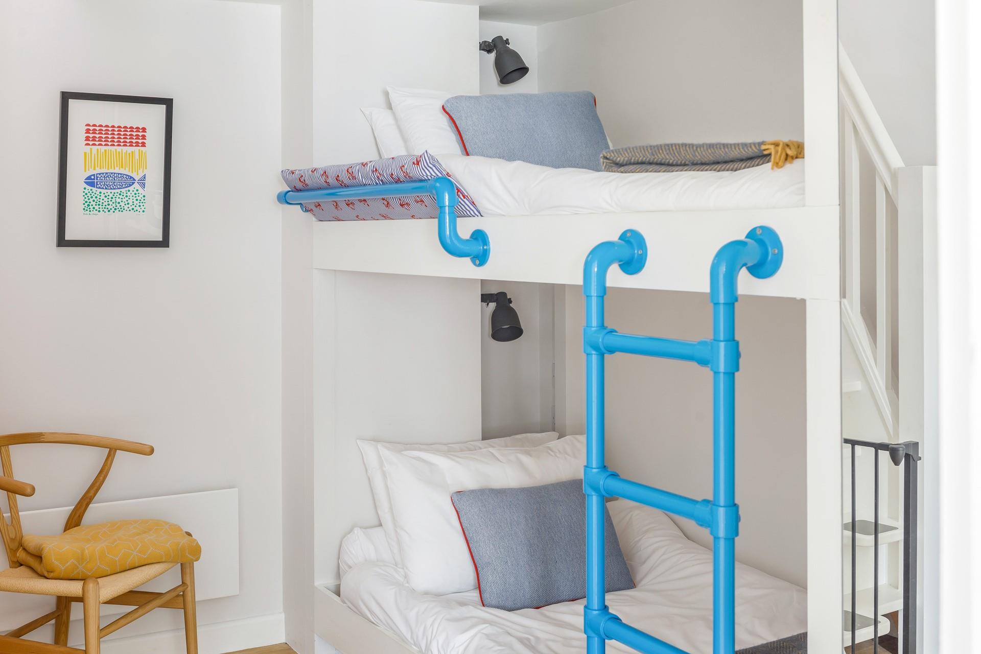 Decorated in calming blue and white tones, the bunk bed room is a lovely space for kids to relax.