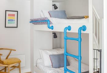 Decorated in calming blue and white tones, the bunk bed room is a lovely space for kids to relax.