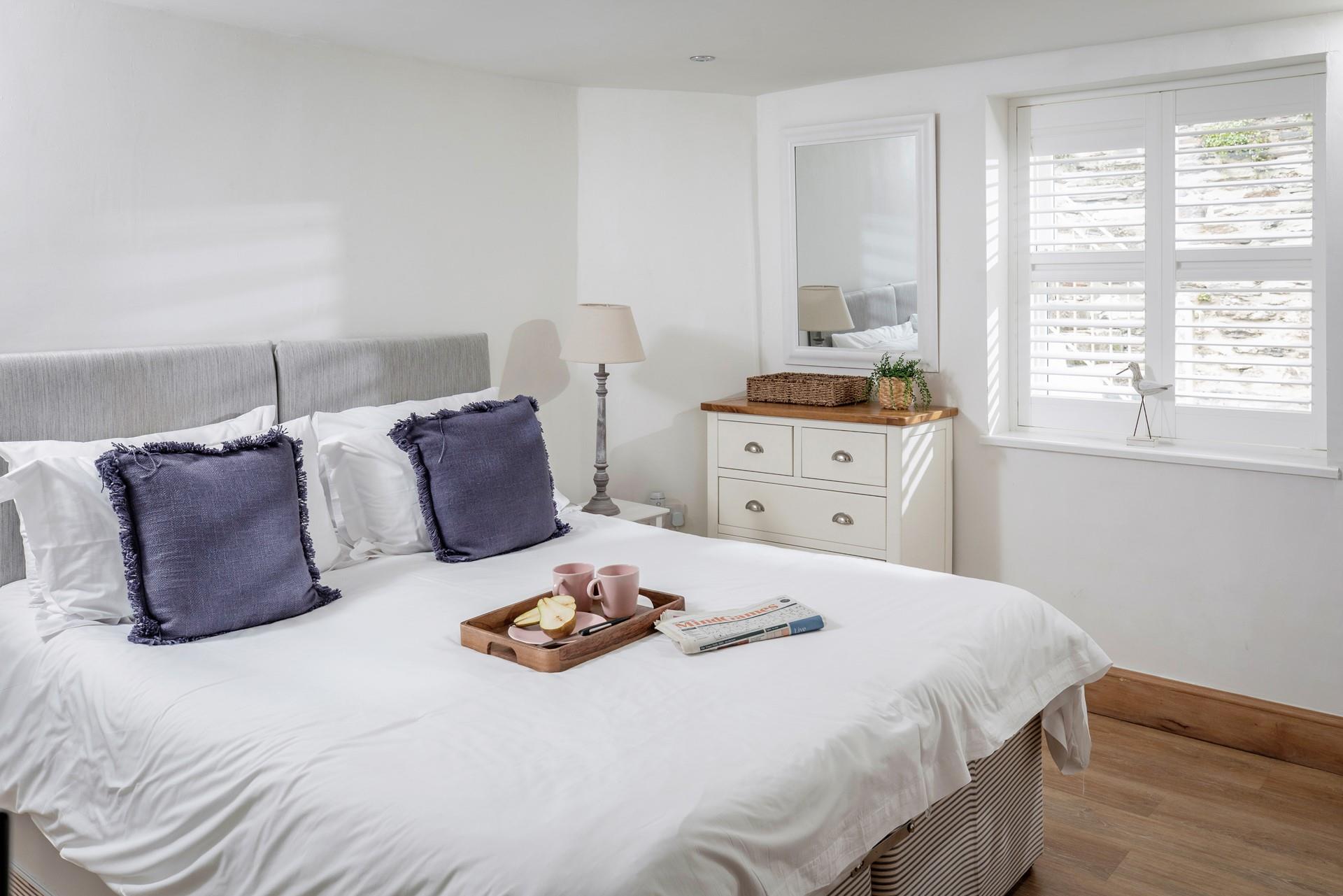 Bedroom 4 has a relaxing ambience, with soft and calming decor and a view out across the patio. 