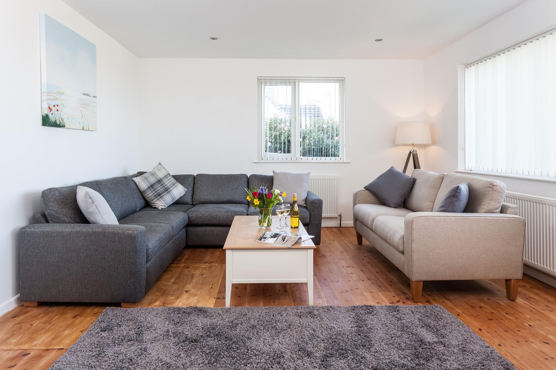 Elegantly designed with exposed floorboards and grey soft furnishings, the living room is a relaxing space to unwind at the end of the day. 