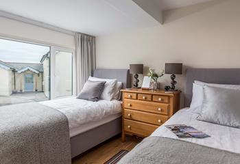 The twin bedroom is decorated with neutral grey tones and creates a calming space to relax.