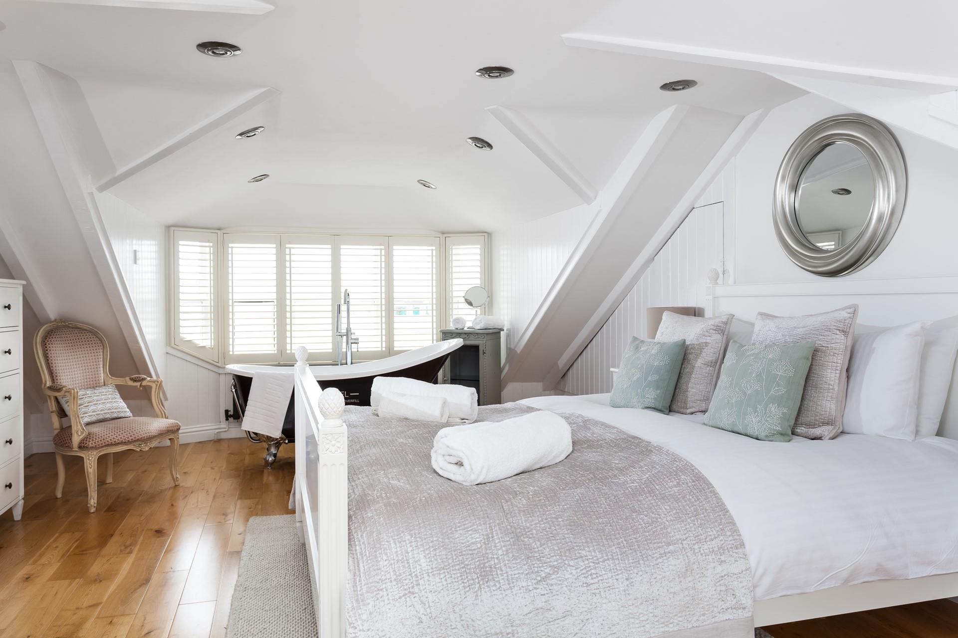 Bedroom 3 has a painted wood king size bed and bedside tables with a Victorian-style roll-top bath.