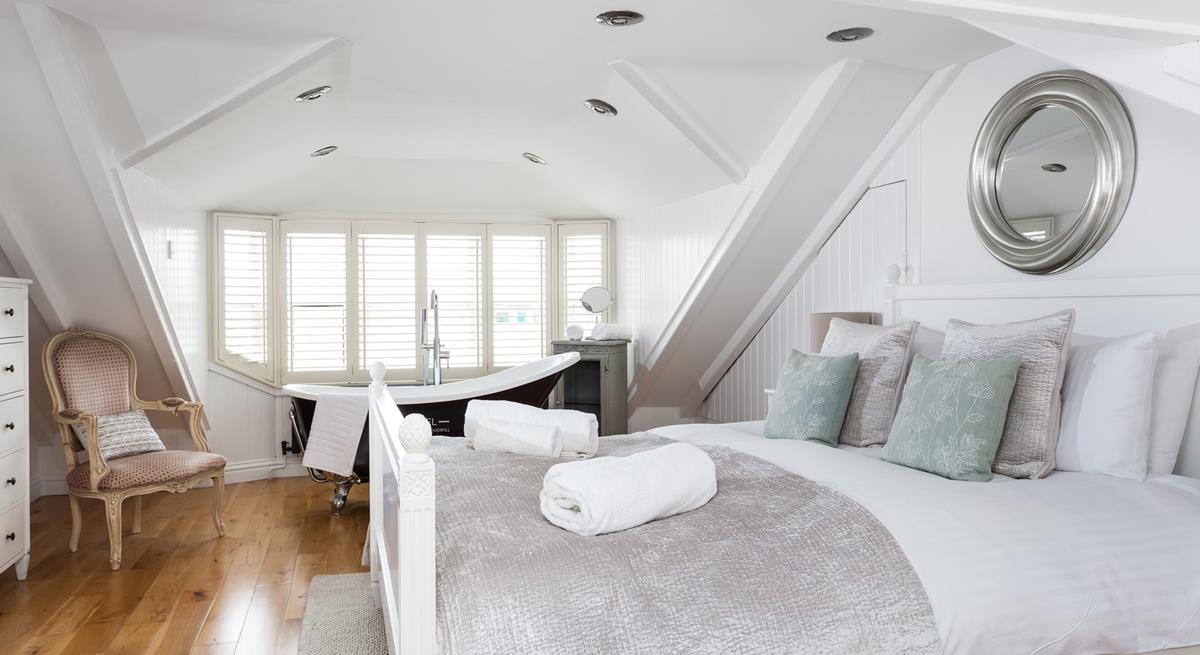 Bedroom 3 has a painted wood king size bed and bedside tables with a Victorian-style roll-top bath.